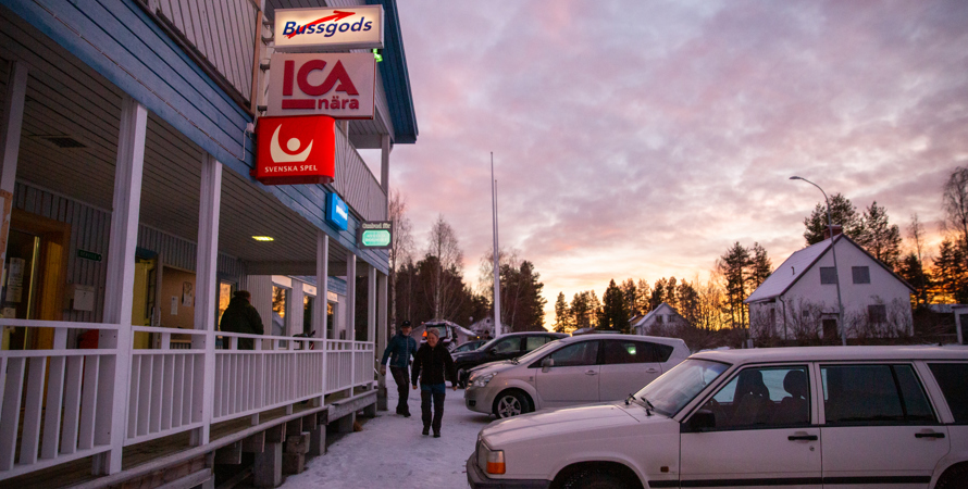 Bil utanför en byggnad med butik, spel, bussgods mm.