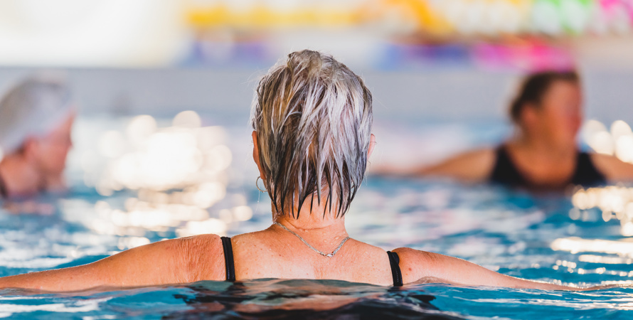 En kvinna med grått hår i en simbassäng.